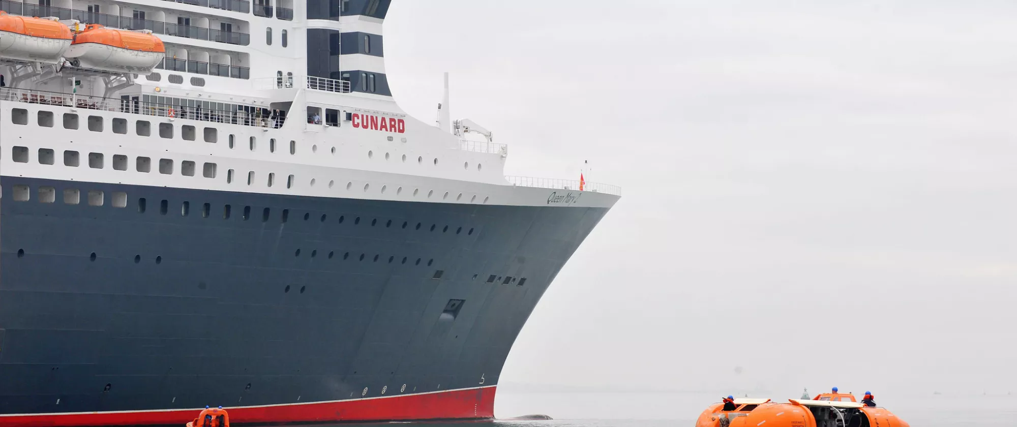 Photo of a transatlantic liner next to a smaller vessel in the water.