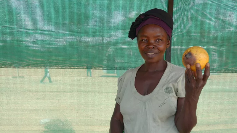 An African women holding a fruit smile to the camera.